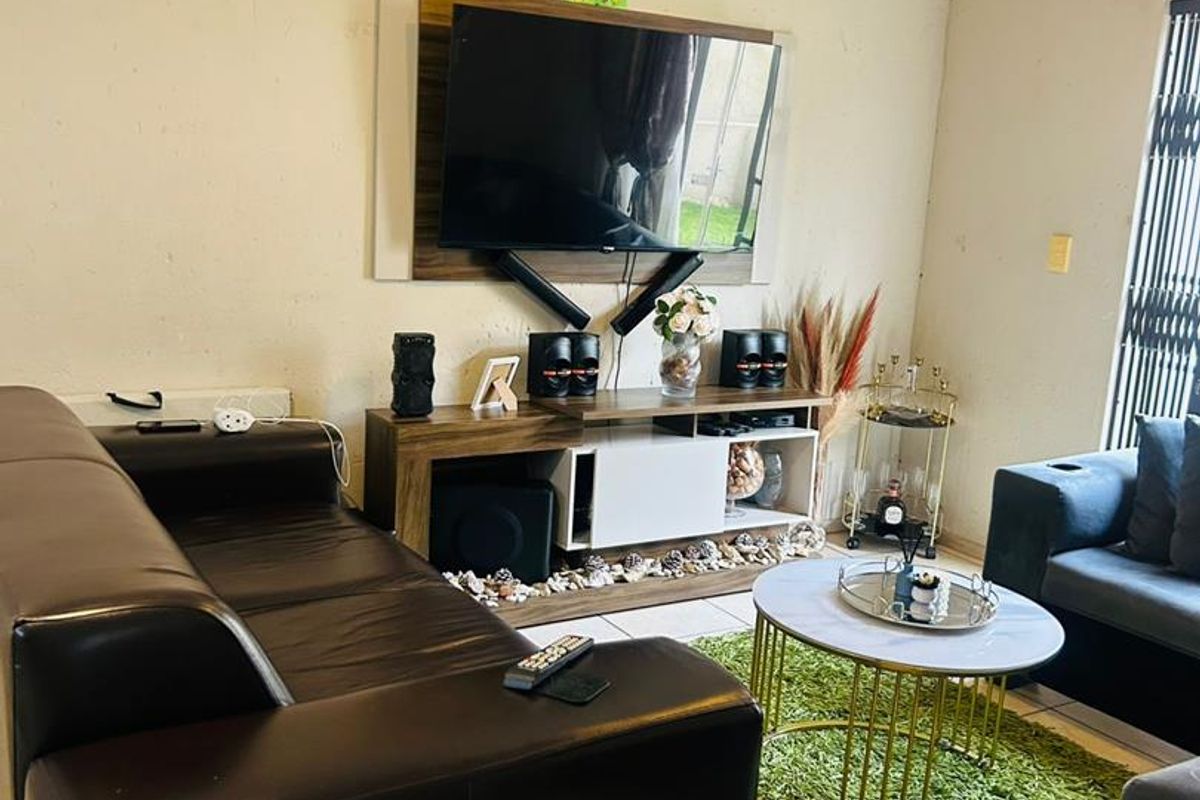 A comfortable living room featuring tiled flooring and a wall-mounted television setup, providing a functional space for relaxation and entertainment.