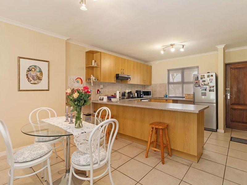 Open plan kitchen and dining area featuring laminate cabinetry, a breakfast bar, and tiled flooring, providing a functional and connected living space.