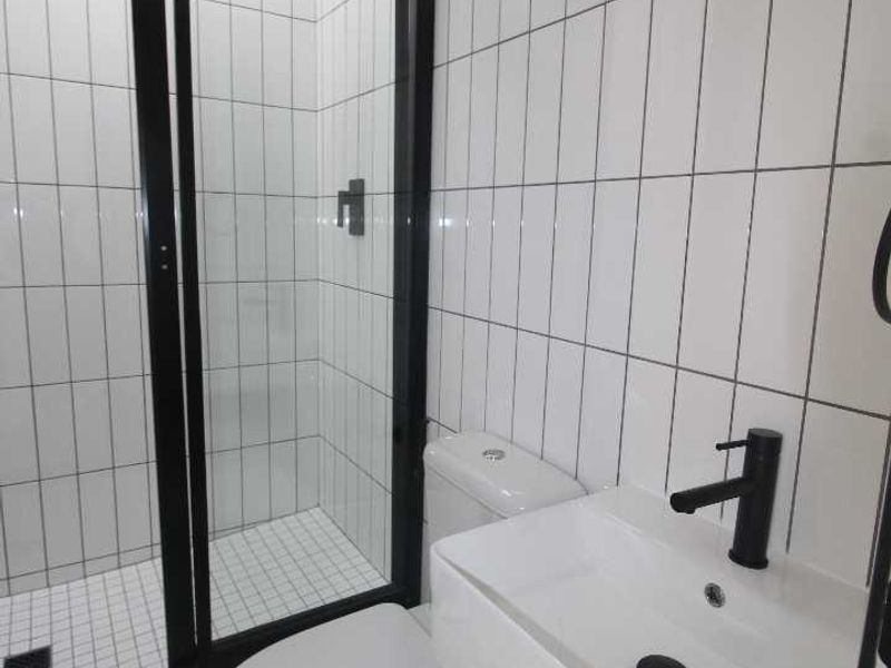 Modern bathroom featuring a walk-in shower with black-framed glass, a wall-mounted vanity, and a skylight providing natural light.