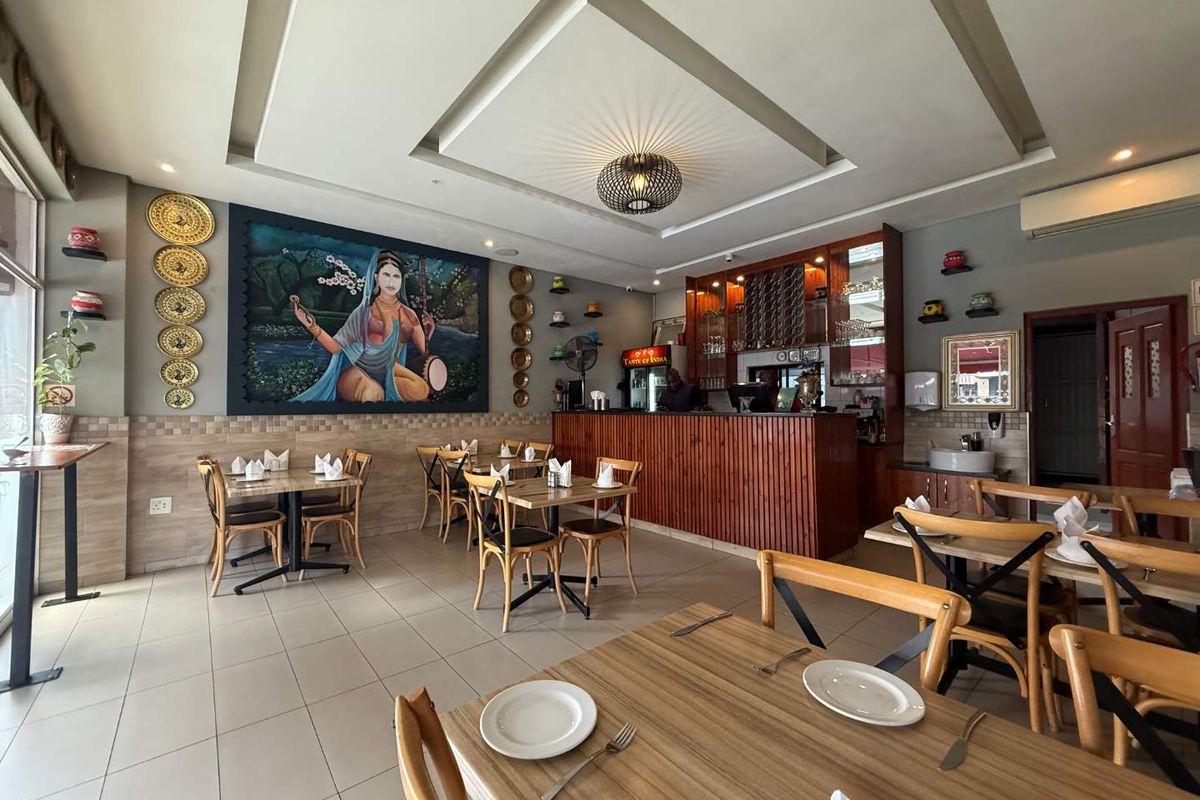 A well-maintained restaurant dining area featuring a built-in bar counter, recessed ceiling lighting, and tiled flooring, suitable for immediate commercial use.