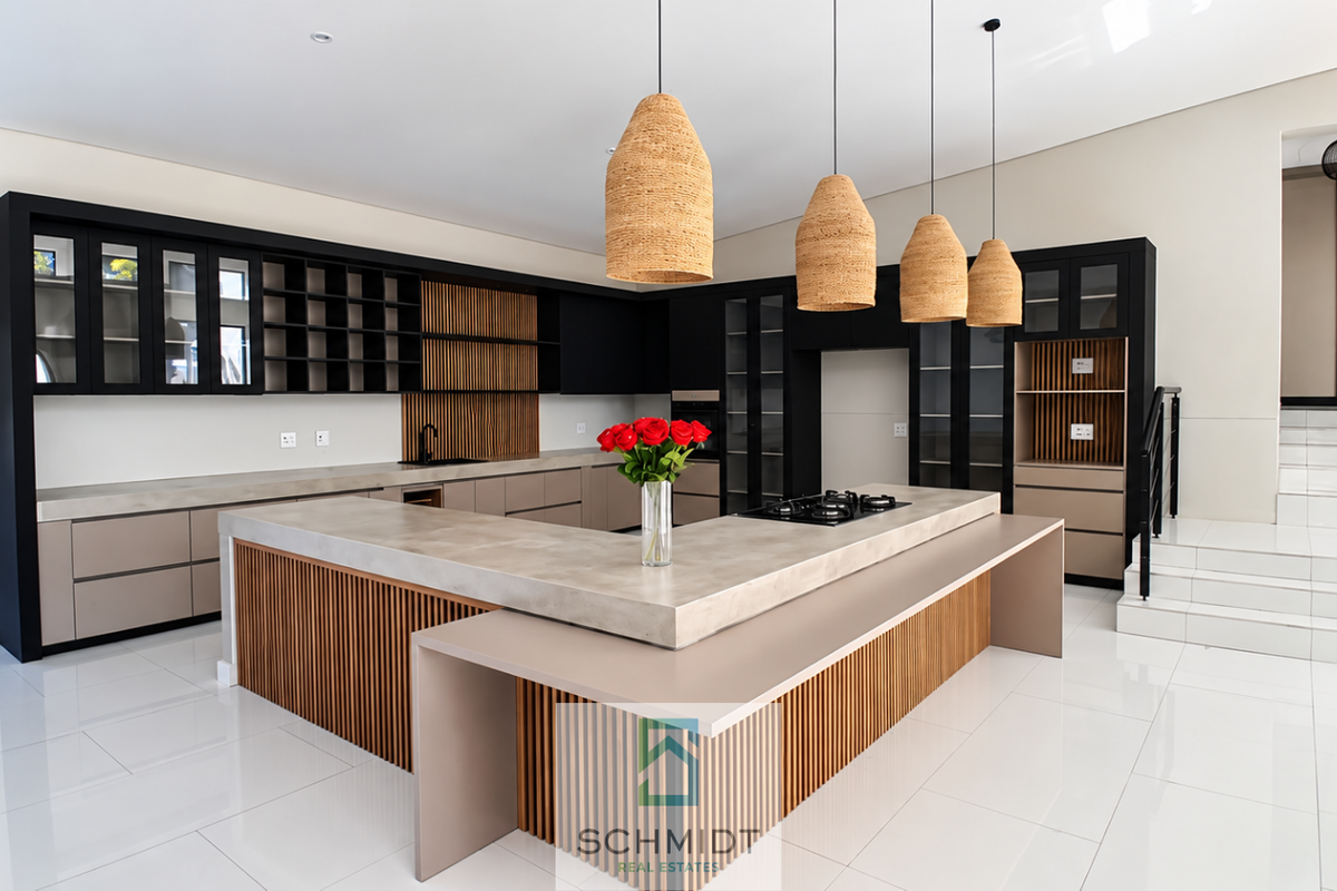 Modern kitchen featuring a large stone island with integrated gas cooktop, custom cabinetry with slatted wood accents, and sleek tiled flooring.