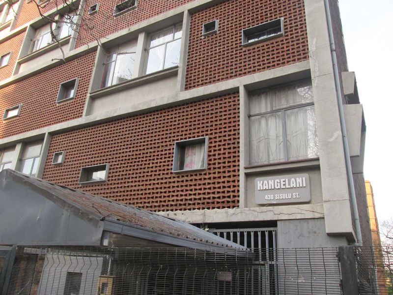 Exterior view of the Kangelani apartment building facade, featuring distinctive brickwork, concrete structural elements, and secure gated entrance.
