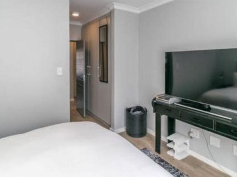 A well-maintained bedroom featuring neutral grey walls, built-in cupboards, and laminate flooring, providing a clean and functional living space.