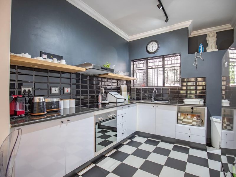 Modern kitchen featuring high-contrast black and white cabinetry, subway tile backsplash, granite countertops, and integrated appliances with a classic checkerboard floor.