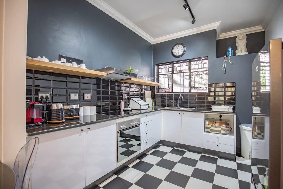 Modern kitchen featuring high-contrast black and white cabinetry, subway tile backsplash, granite countertops, and integrated appliances with a classic checkerboard floor.