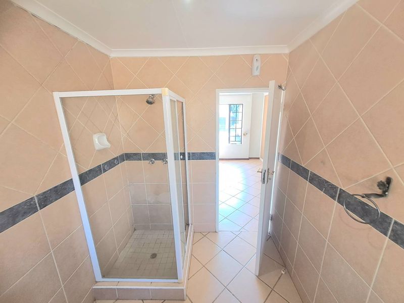 A functional bathroom featuring a shower enclosure with tiled walls and flooring, presenting a clean, neutral space ready for modern updates.