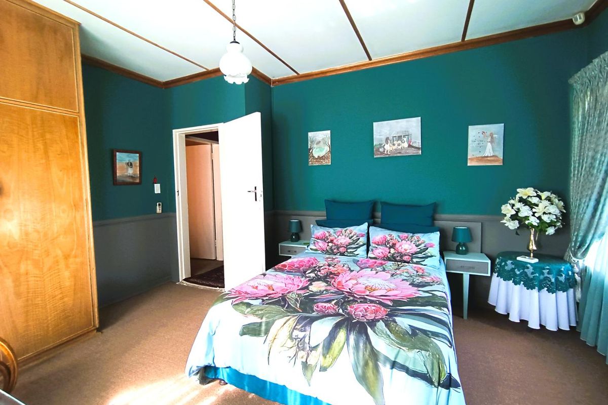 A bedroom featuring built-in wooden cabinetry, teal painted walls with wainscoting, and a traditional ceiling design.