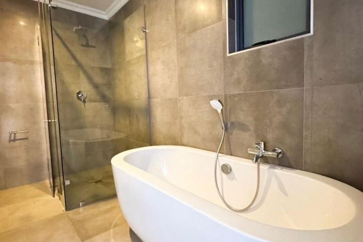 Modern bathroom featuring a sleek freestanding bathtub, a separate glass-enclosed shower, and contemporary large-format wall and floor tiling.