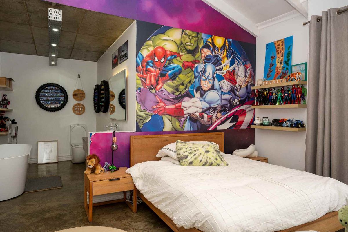A bedroom featuring polished concrete flooring, an exposed concrete ceiling, and an open-plan en-suite bathroom area with a freestanding bathtub.
