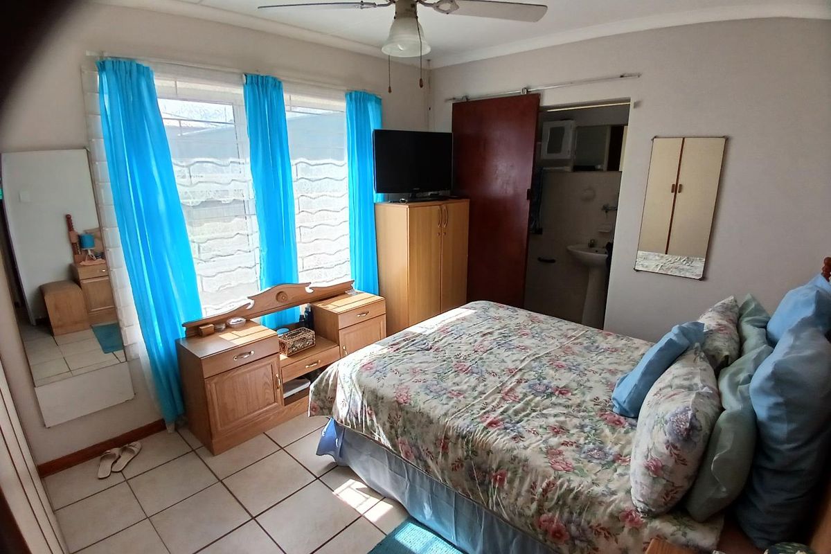 A bedroom featuring tiled flooring, a ceiling fan, and an en-suite bathroom access point.