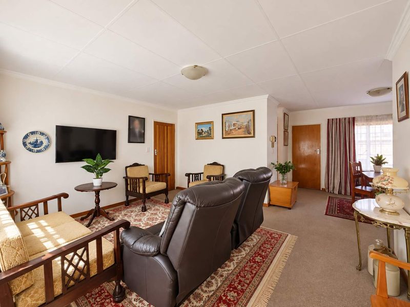 A comfortable living area featuring neutral walls, carpeted flooring, and a tiled ceiling, providing a functional and well-maintained space for relaxation.