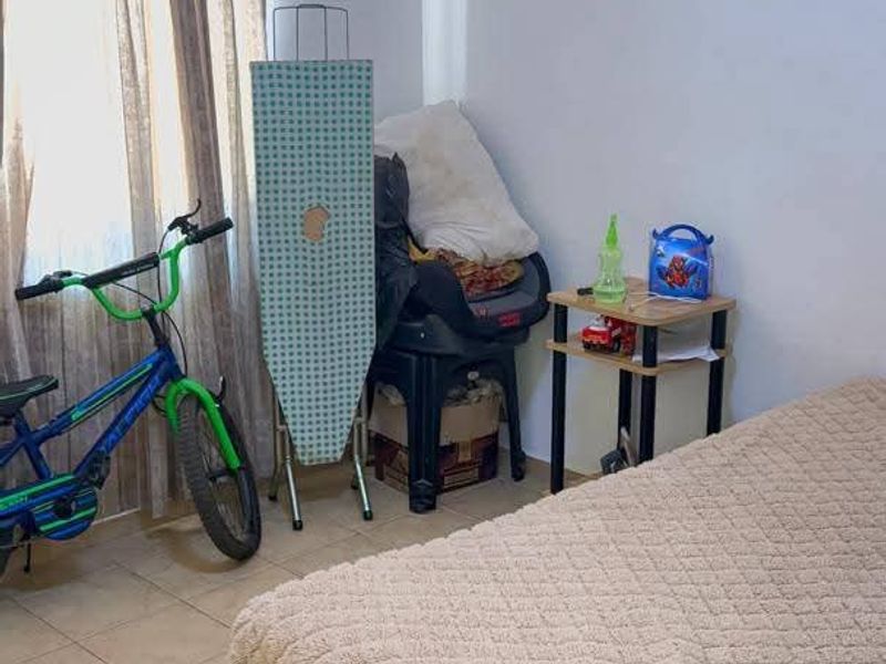 A bedroom featuring tiled flooring and a window with installed curtain rods.