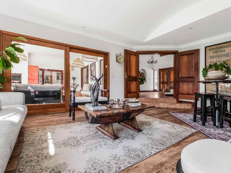 Spacious living area featuring warm hardwood flooring, elegant wooden door frames, and a vaulted ceiling with crown molding, creating a welcoming and sophisticated atmosphere.