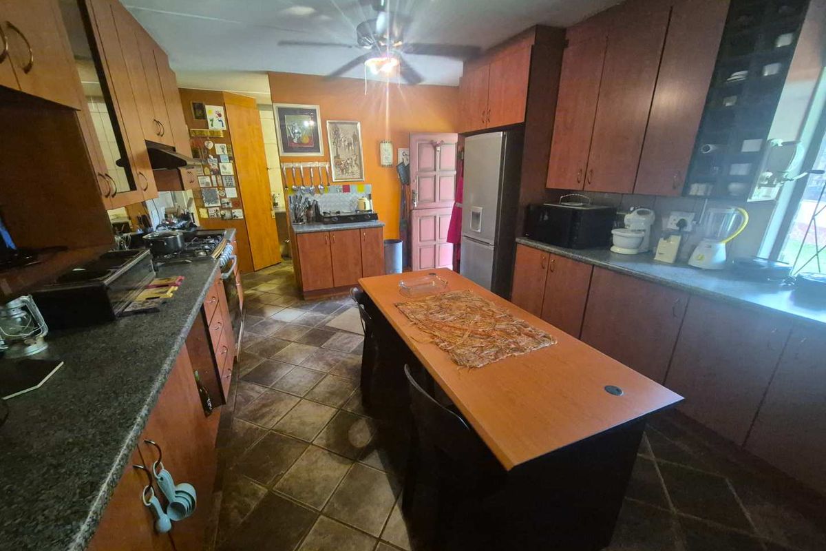 A functional kitchen featuring wood-finish cabinetry, dark countertops, a central island, and tiled flooring, providing ample storage and workspace.
