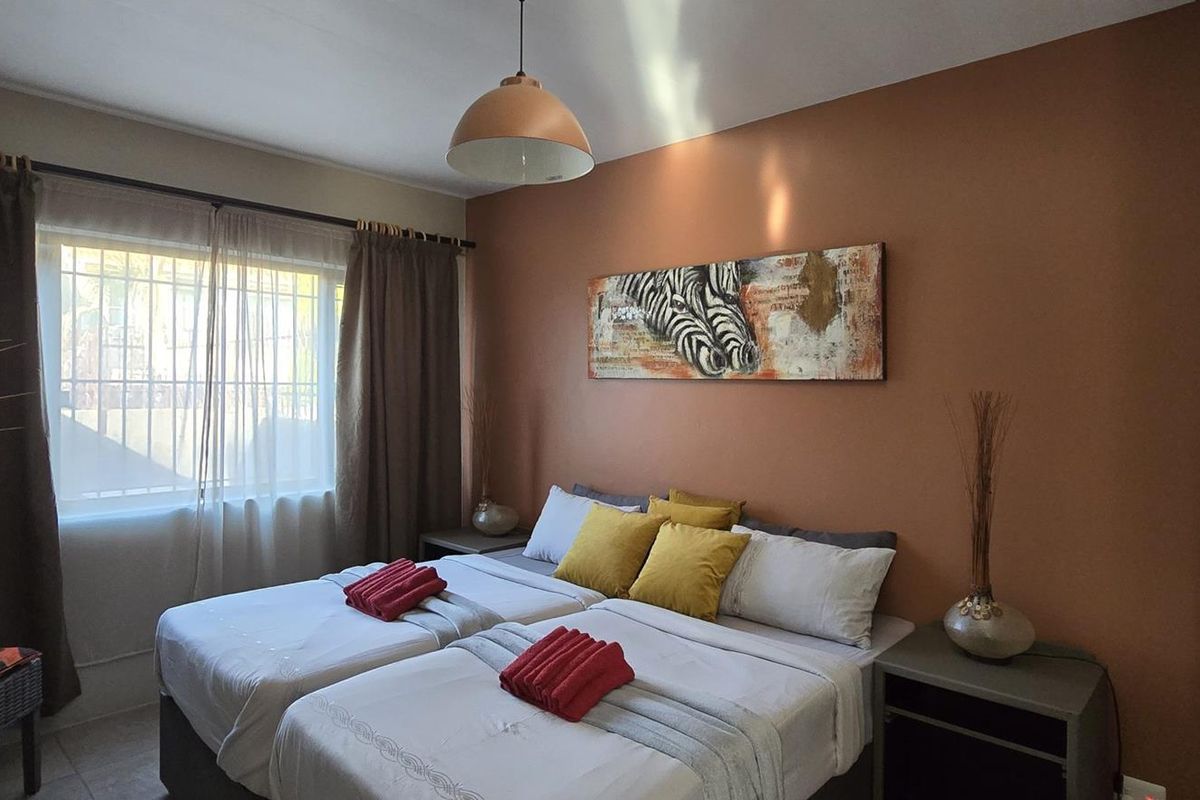 A bedroom featuring a built-in wardrobe, a pendant light fixture, and a window with curtain rods.