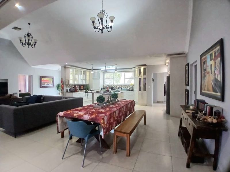 Spacious open-plan living and dining area featuring a vaulted ceiling, tiled floors, and a well-appointed kitchen with a central island.