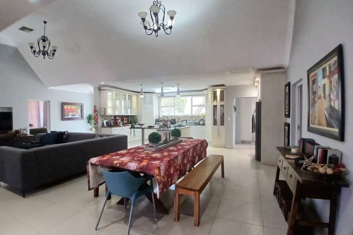 Spacious open-plan living and dining area featuring a vaulted ceiling, tiled floors, and a well-appointed kitchen with a central island.