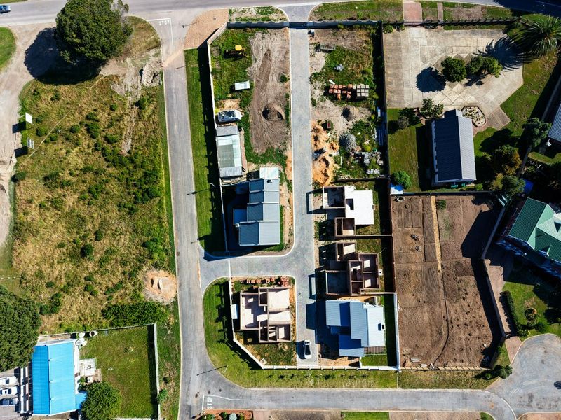 Aerial view of a residential development site showing multiple properties in various stages of construction, paved access roads, and boundary walling.