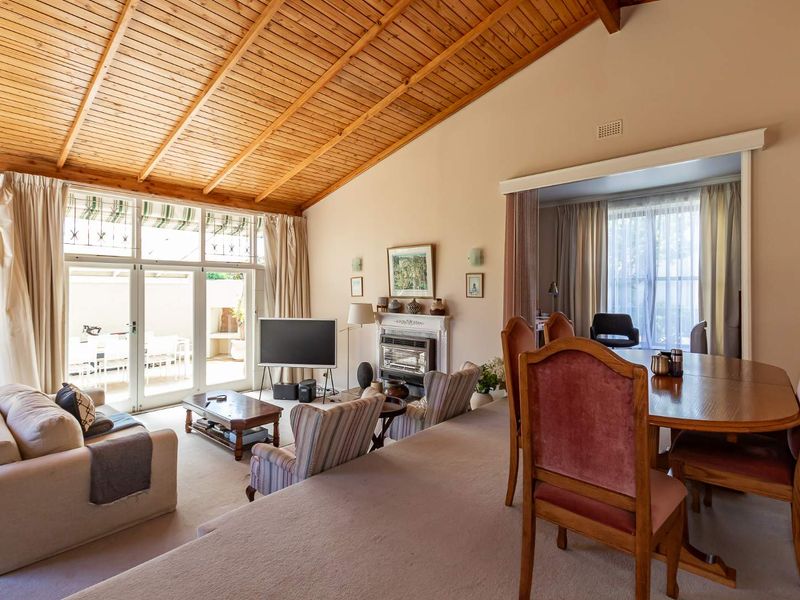 Spacious open-plan living and dining area featuring a vaulted timber ceiling, fireplace, and large sliding glass doors providing access to the outdoor patio.