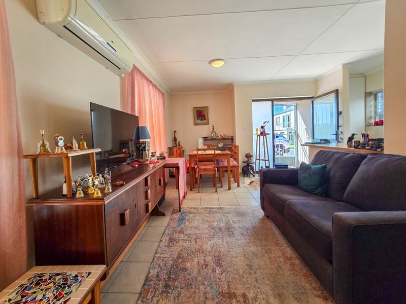Open-plan living and dining area featuring tiled flooring, a split-system air conditioner, and direct access to the exterior through a sliding glass door.