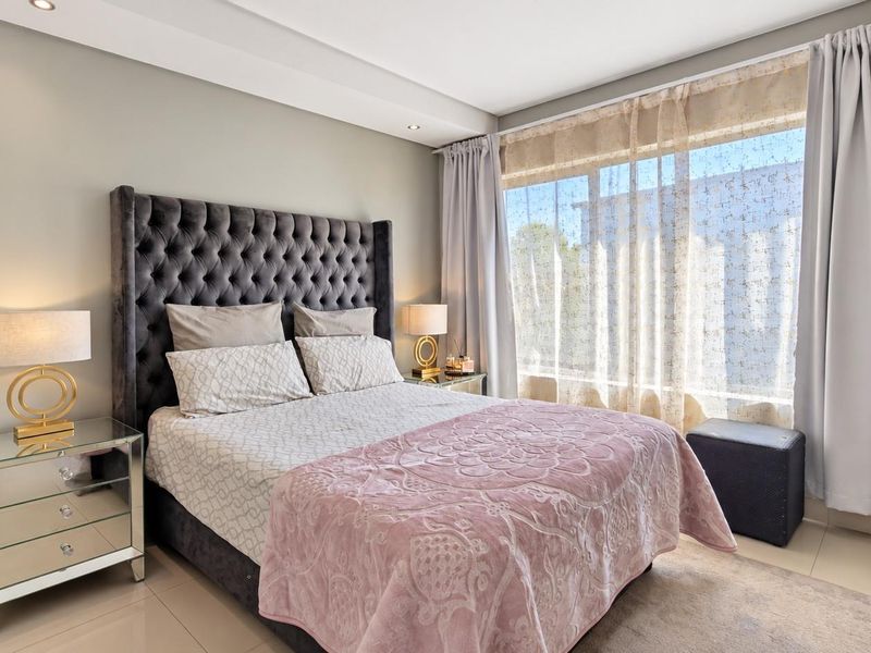 A well-maintained bedroom featuring tiled flooring, recessed downlighting, and a built-in wardrobe, offering a clean and comfortable living space.