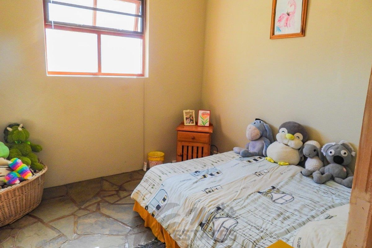 A bedroom featuring natural stone flooring and a large window, providing a rustic and functional living space.