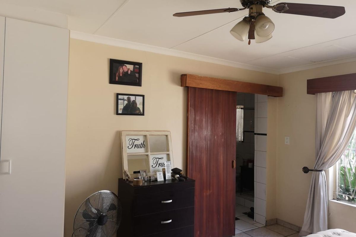 A bedroom featuring a ceiling fan, tiled flooring, built-in wardrobe, and a sliding wooden door leading to an adjacent space.