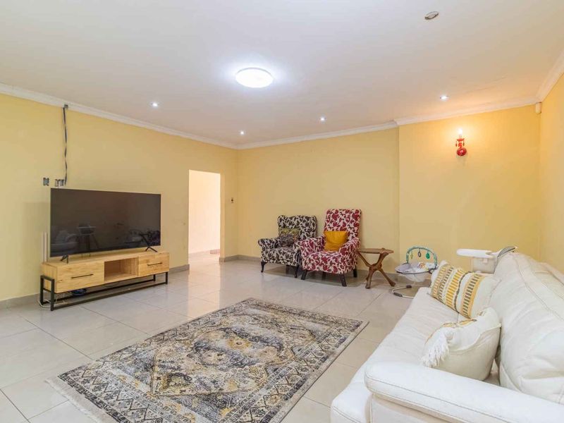 A spacious living room featuring tiled flooring, recessed downlighting, and coved ceilings, providing a functional and open living area.