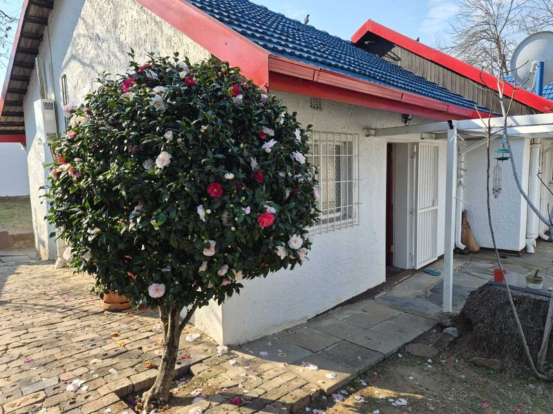 Rear exterior view of the cottage featuring a tiled roof, security bars on windows, and a paved walkway leading to the entrance.