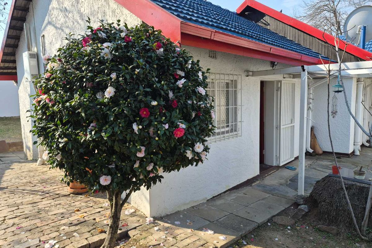 Rear exterior view of the cottage featuring a tiled roof, security bars on windows, and a paved walkway leading to the entrance.