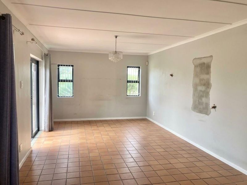 Spacious, empty living area featuring tiled flooring, large sliding glass doors, and natural light, ready for renovation and personalization.