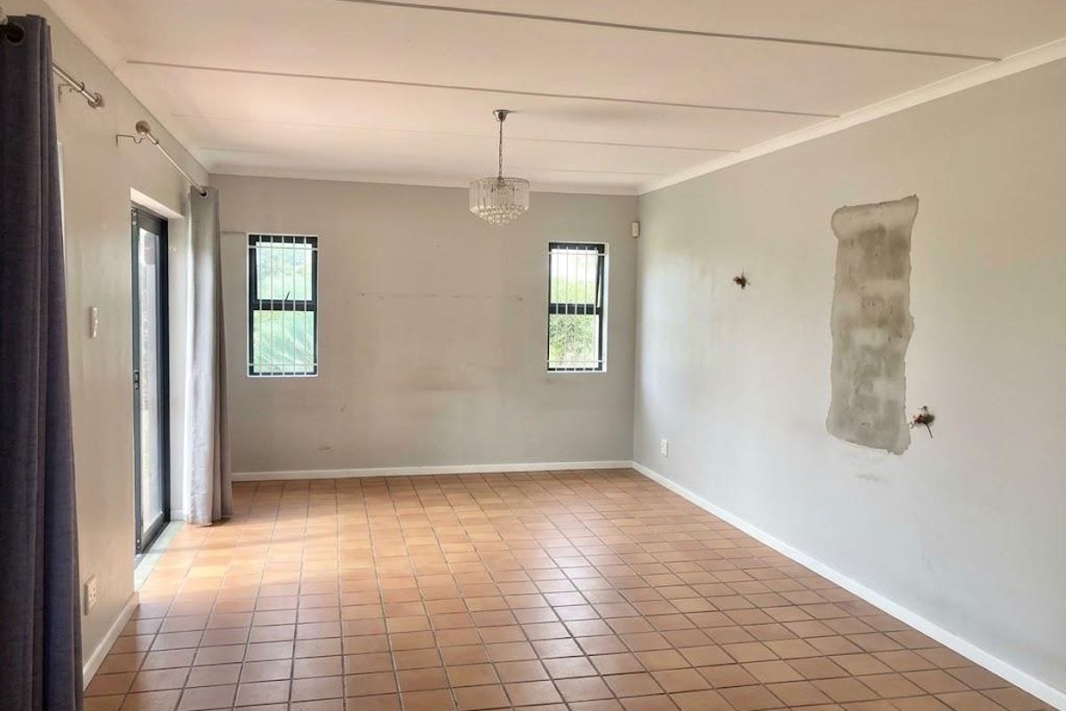 Spacious, empty living area featuring tiled flooring, large sliding glass doors, and natural light, ready for renovation and personalization.