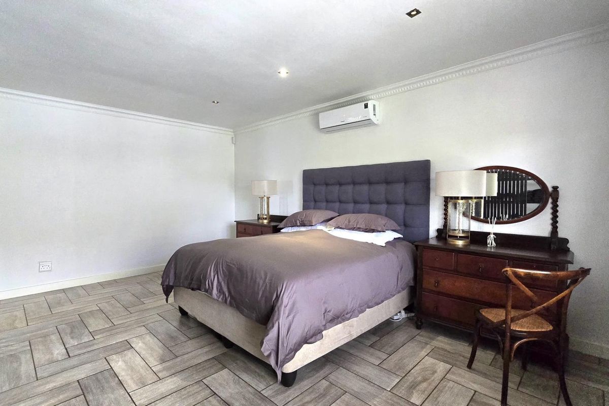 Spacious bedroom featuring modern herringbone tile flooring, crown molding, recessed lighting, and a wall-mounted air conditioning unit.