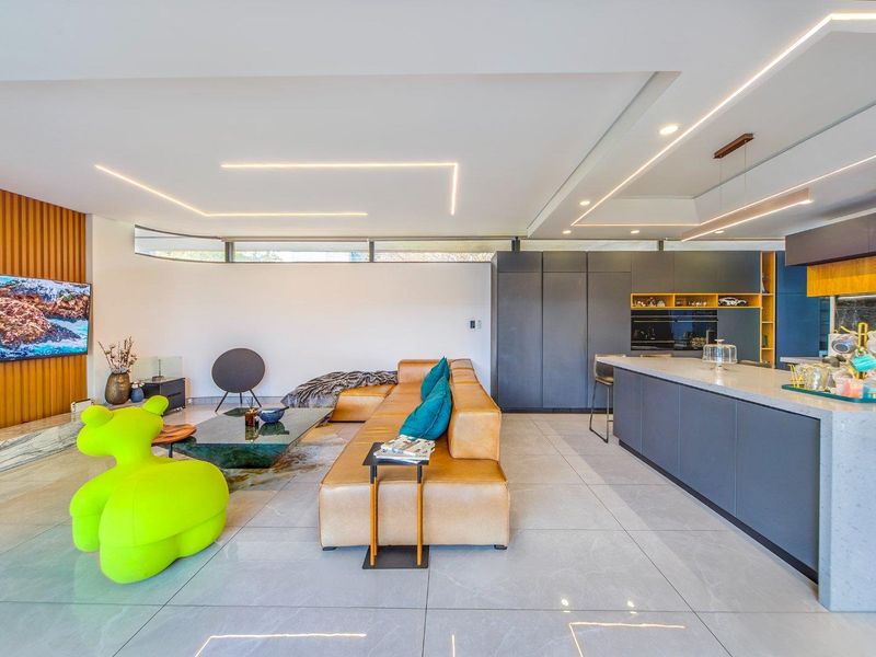 Modern open-plan living and kitchen area featuring sleek cabinetry, stone island bench, recessed lighting, and elegant timber wall accents.