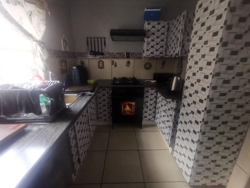 Compact kitchen featuring a gas hob, extractor fan, built-in cabinetry, and tiled splashback, offering a functional layout with potential for modern updates.