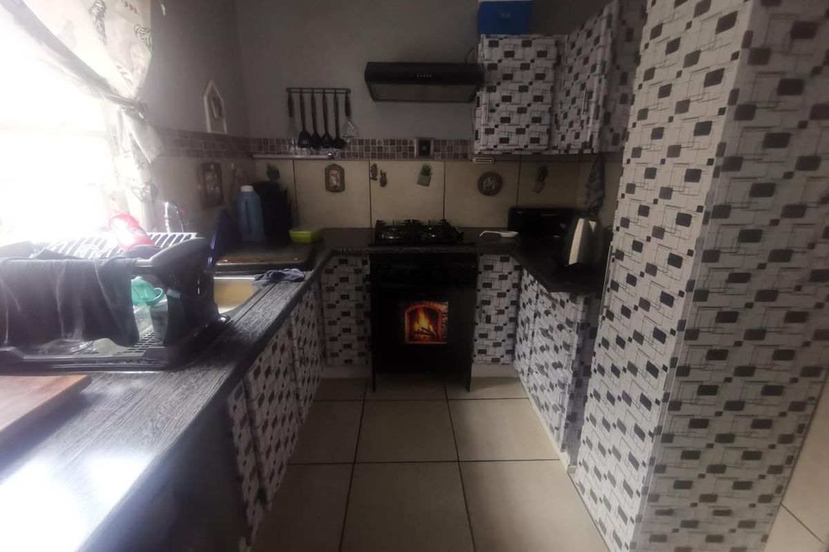 Compact kitchen featuring a gas hob, extractor fan, built-in cabinetry, and tiled splashback, offering a functional layout with potential for modern updates.
