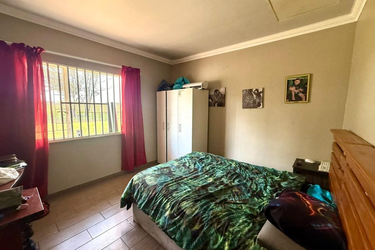 A functional bedroom featuring tiled flooring, security bars on the window, and a ceiling access hatch.