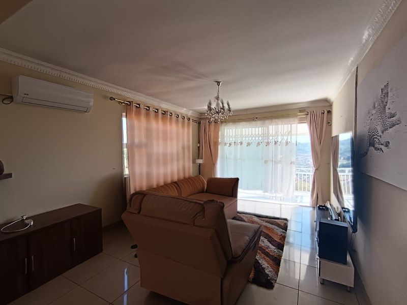 A comfortable living room featuring tiled flooring, air conditioning, and a sliding glass door that provides access to an outdoor balcony area.