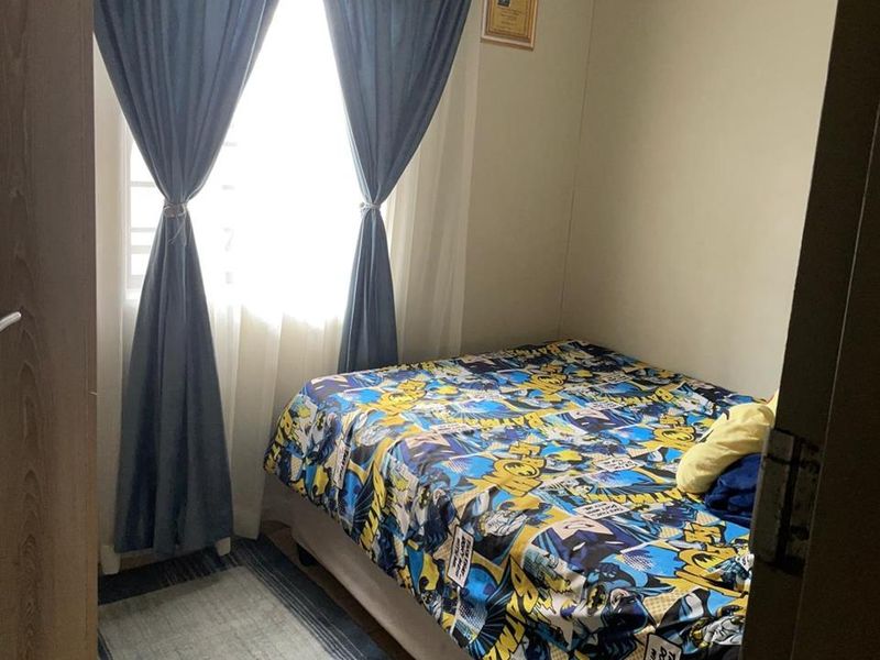 A compact bedroom featuring a window with curtains, providing natural light and a functional space for a single bed.