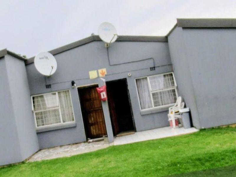 Rear exterior view of the townhouse featuring a tiled patio area, security gate, and satellite dish installation.