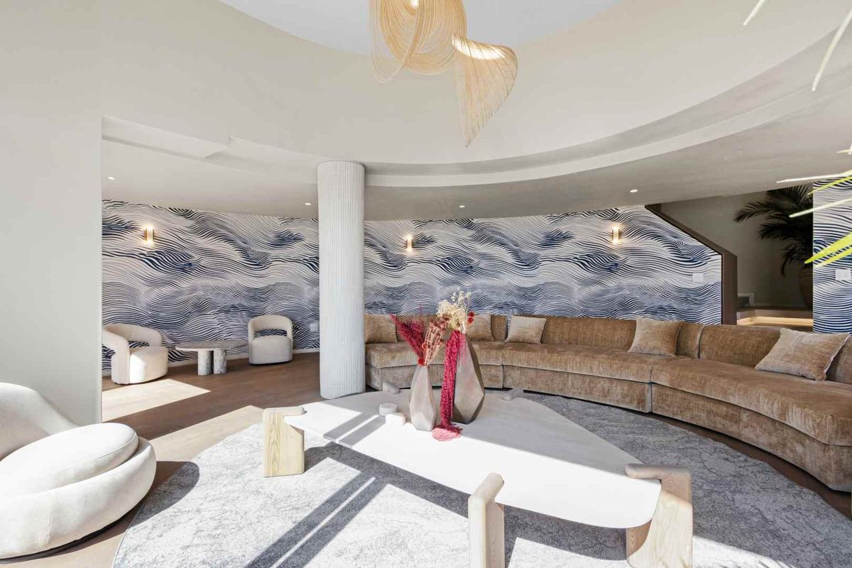 Spacious living area featuring a curved architectural design, recessed ceiling detail, and decorative wallpaper, creating a sophisticated and modern atmosphere.