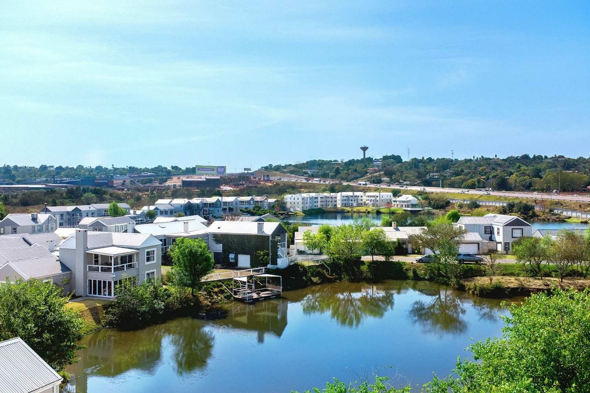 An elevated aerial view of a residential estate featuring multiple homes situated around a scenic lake.