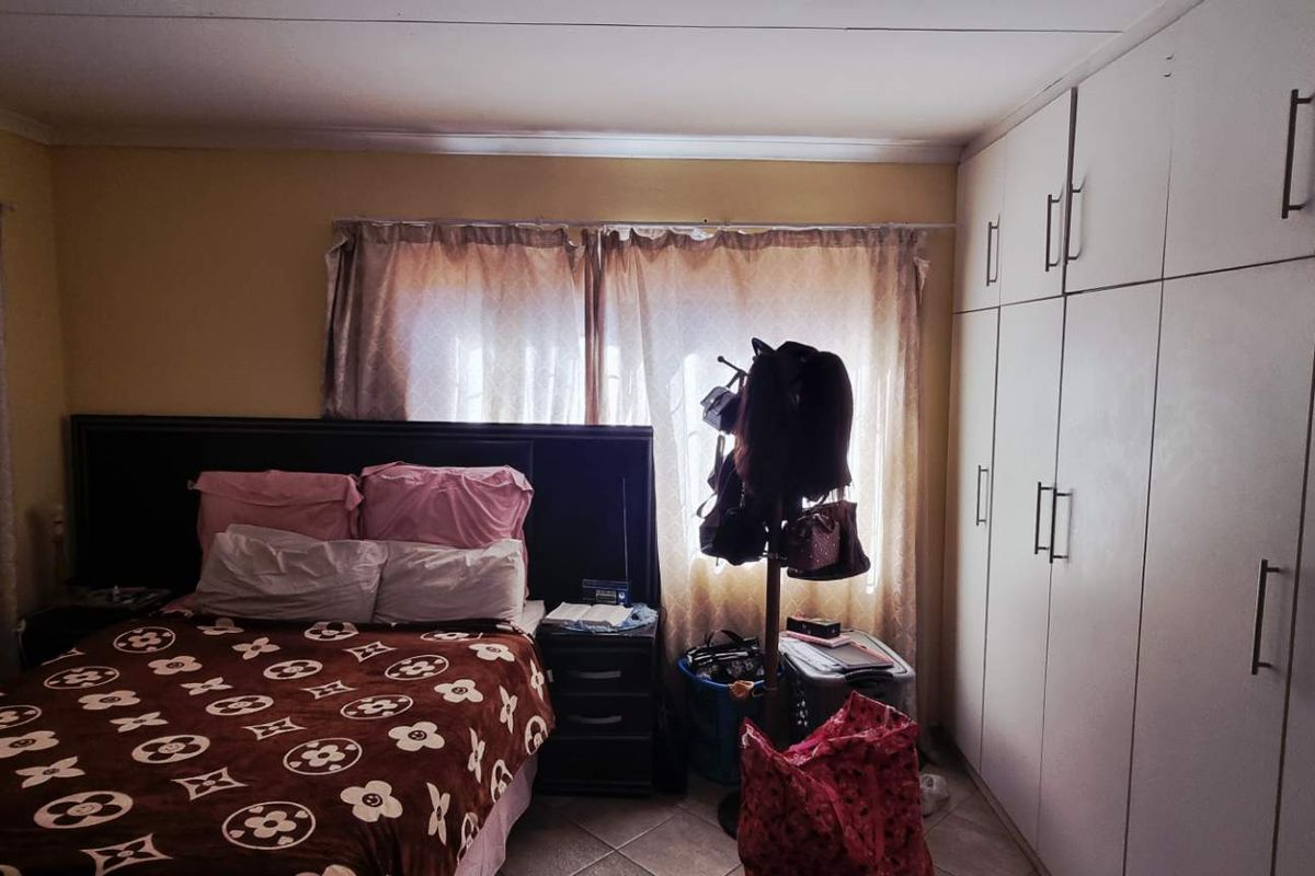 A bedroom featuring built-in floor-to-ceiling wardrobes and tiled flooring, offering functional storage space.