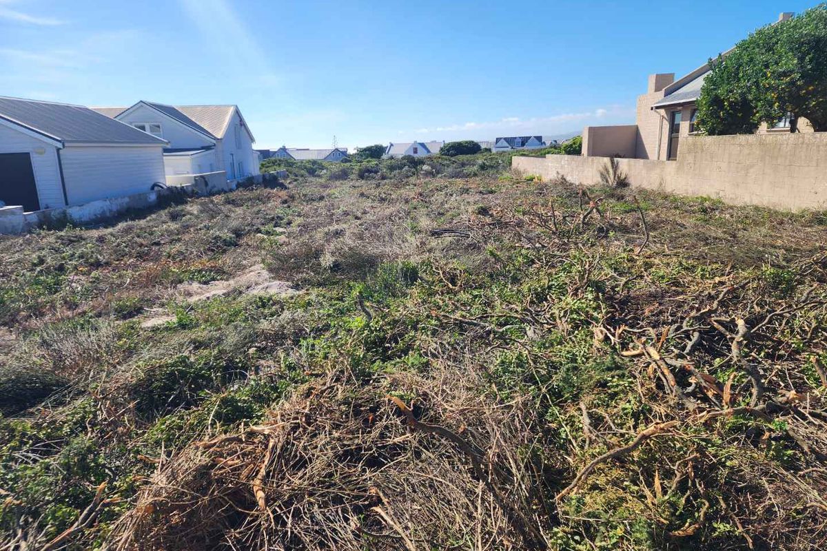 A vacant residential plot featuring cleared vegetation and established boundary walls, situated in a developed neighborhood setting.