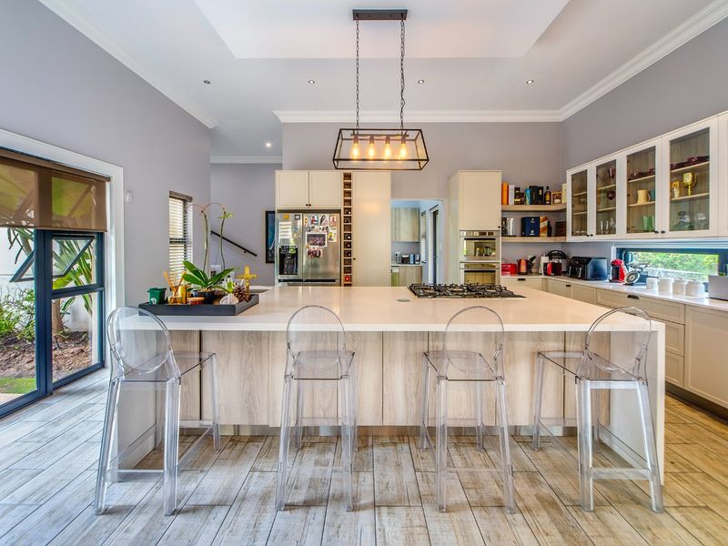 Modern kitchen featuring a large central island with gas hob, ample cabinetry, glass-fronted display units, and direct access to the outdoor area.