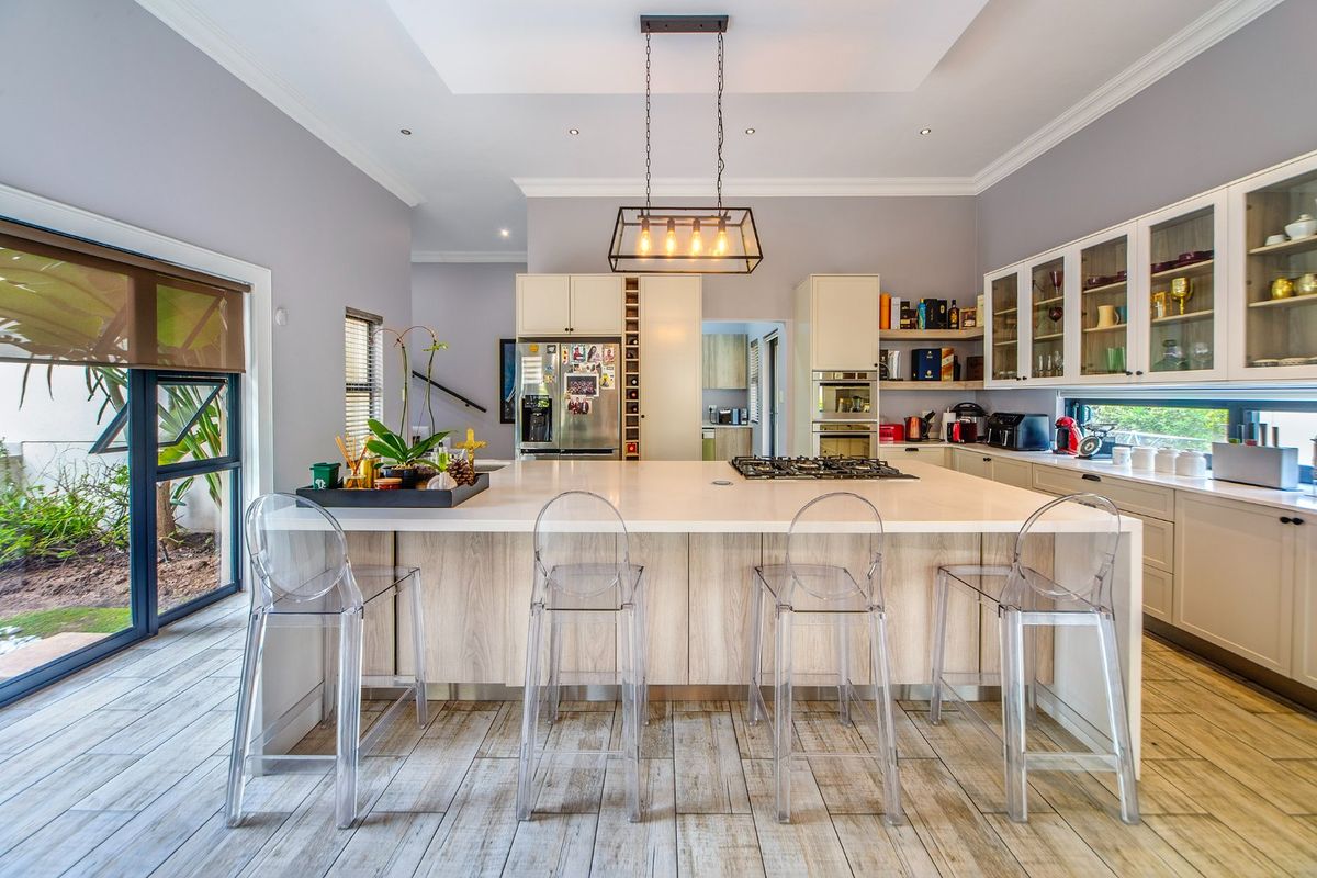 Modern kitchen featuring a large central island with gas hob, ample cabinetry, glass-fronted display units, and direct access to the outdoor area.
