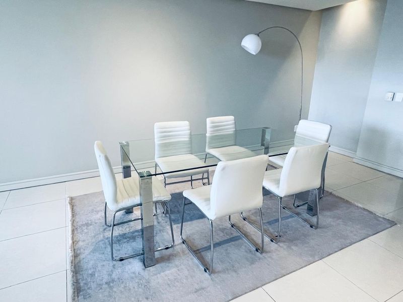 A bright and modern dining area featuring neutral tiled flooring and recessed ceiling lighting, providing a clean and minimalist space for meals.