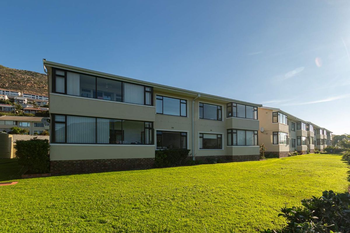 Exterior view of a multi-story apartment complex featuring large windows and a well-maintained lawn area.