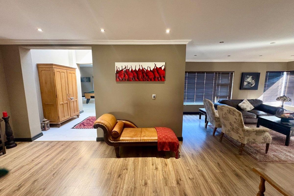 Spacious open-plan living area featuring laminate flooring, recessed downlighting, and large windows with venetian blinds, creating a bright and inviting atmosphere.
