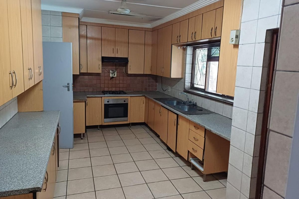 A functional kitchen featuring extensive laminate cabinetry, granite countertops, built-in oven, gas hob, and tiled flooring, offering a solid foundation for modern updates.